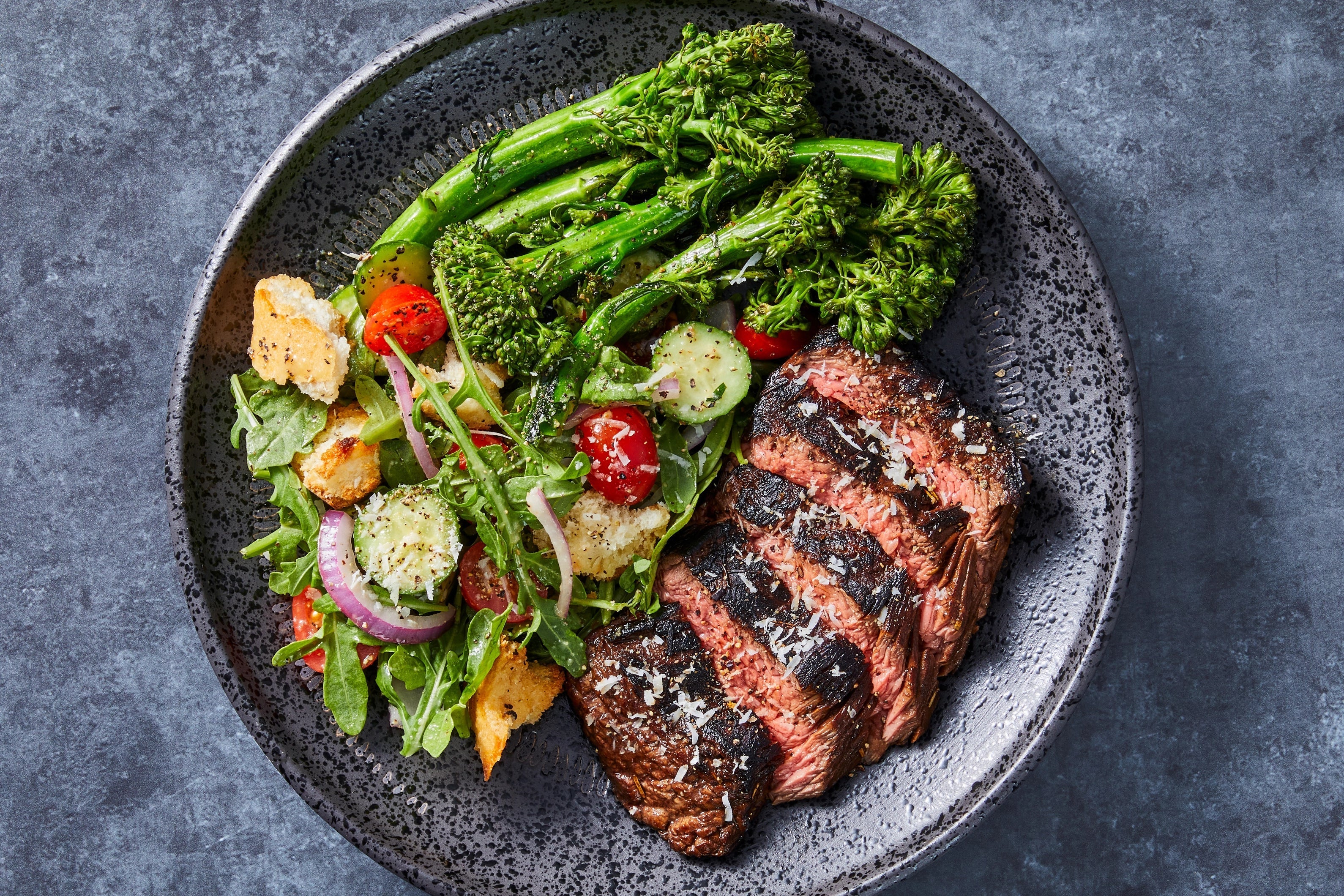 A grass-fed ribeye steak with herb butter and charred broccoli on a dark plate — a low deuterium dinner recipe